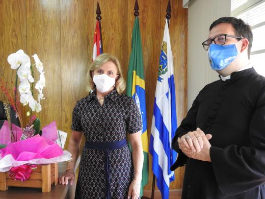 Regina recebe o Padre Alex em seu gabinete.